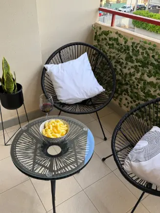 Moderner Balkon mit schwarzen Loungesesseln, rundem Tisch, Kissen und stimmungsvoller Outdoor-Deko