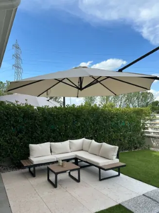 Gartenlounge mit hellem Polster und gro&szlig;em Sonnenschirm