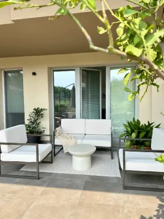 &Uuml;berdachte Terrasse mit Outdoor-Sofa, Beistelltisch und Pflanzen in hellem, modernem Stil.